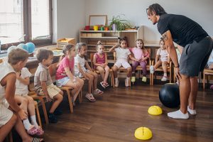 Animateur périscolaire encadrant un groupe d'enfants lors d'une activité collective en école maternelle, illustration d'un article consacré à la professionnalisation et à la réforme du métier d'animateur vacataire.